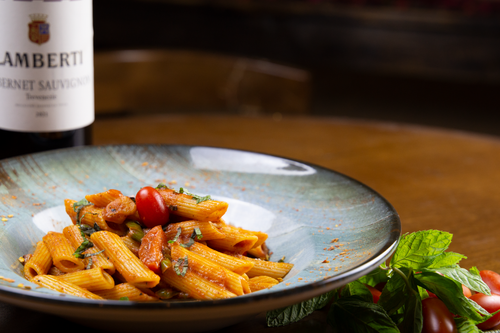 Free A vibrant plate of Italian penne pasta with tomato, basil, and paired wine. Stock Photo