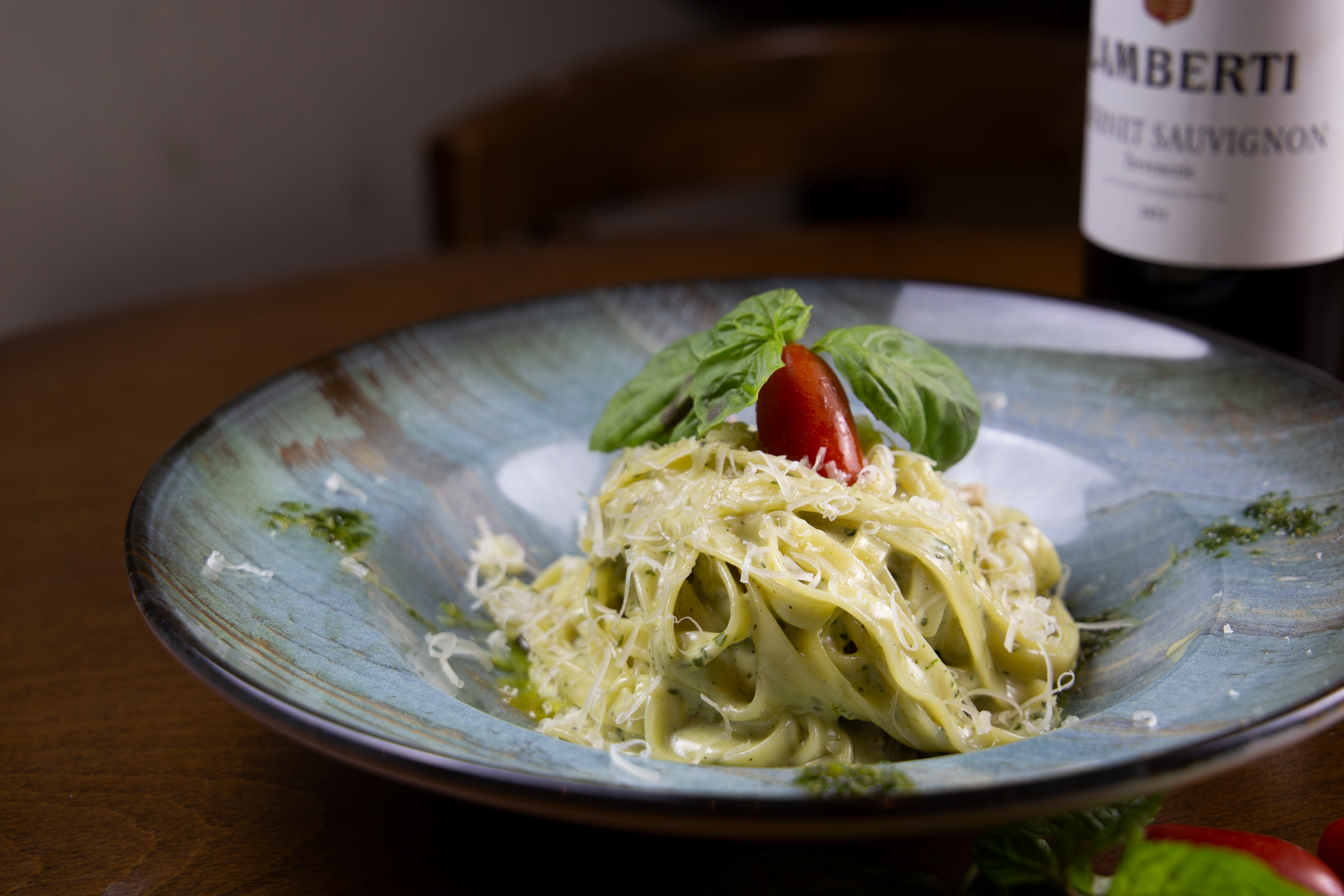 Creamy Italian pasta with basil and tomato garnishes, served fresh on a ceramic plate in Amman.