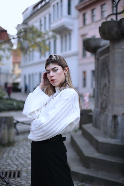 Fashionable woman posing in urban Berlin with a classic European architectural background.