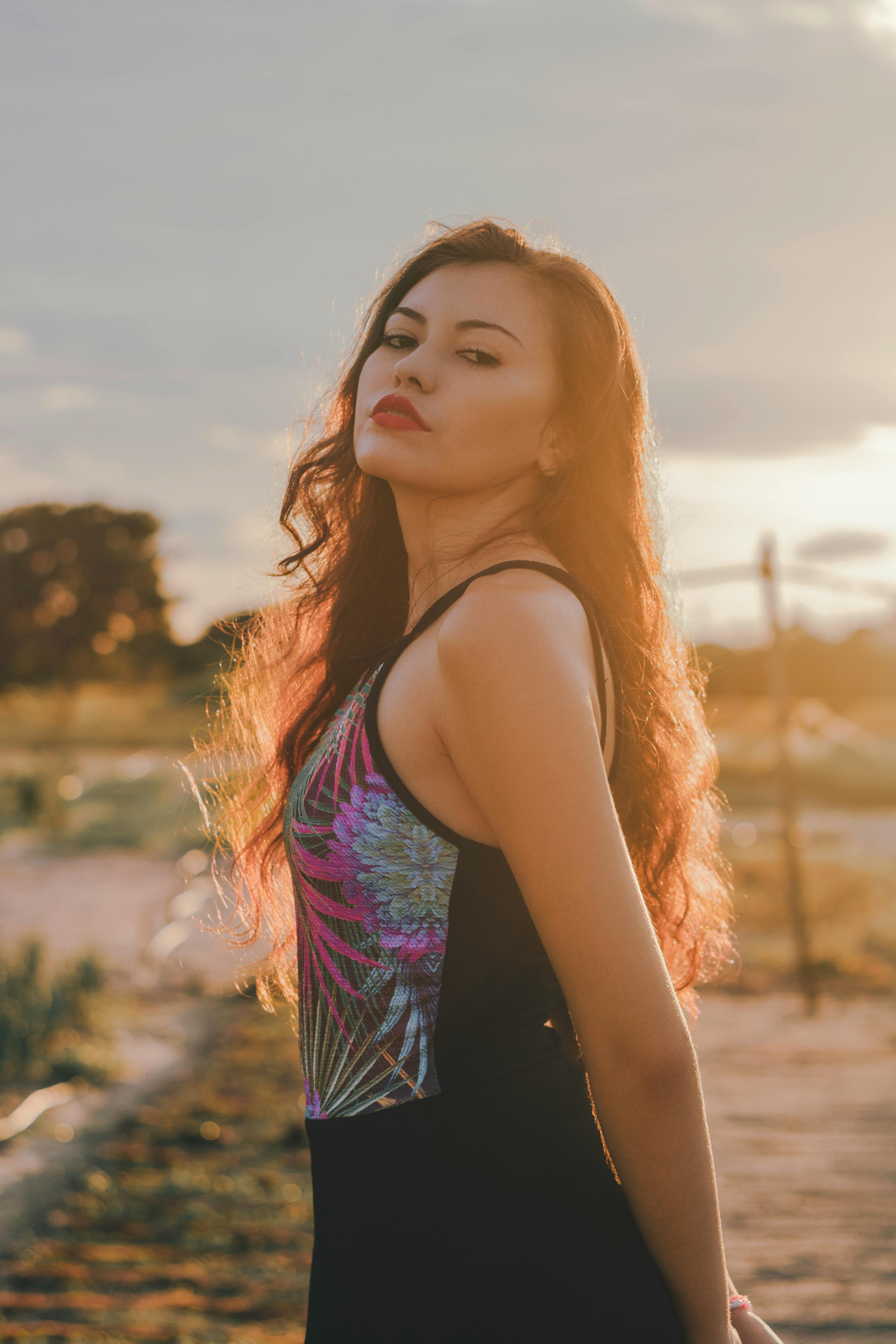 夕阳的金光中，一位秀发飘逸的美丽女子优雅地摆着姿势