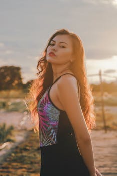 夕阳的金光中，一位秀发飘逸的美丽女子优雅地摆着姿势