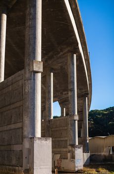 Photo by Robert So Detailed view of a modern concrete bridge structure showcasing pillars and beams under a clear blue sky.