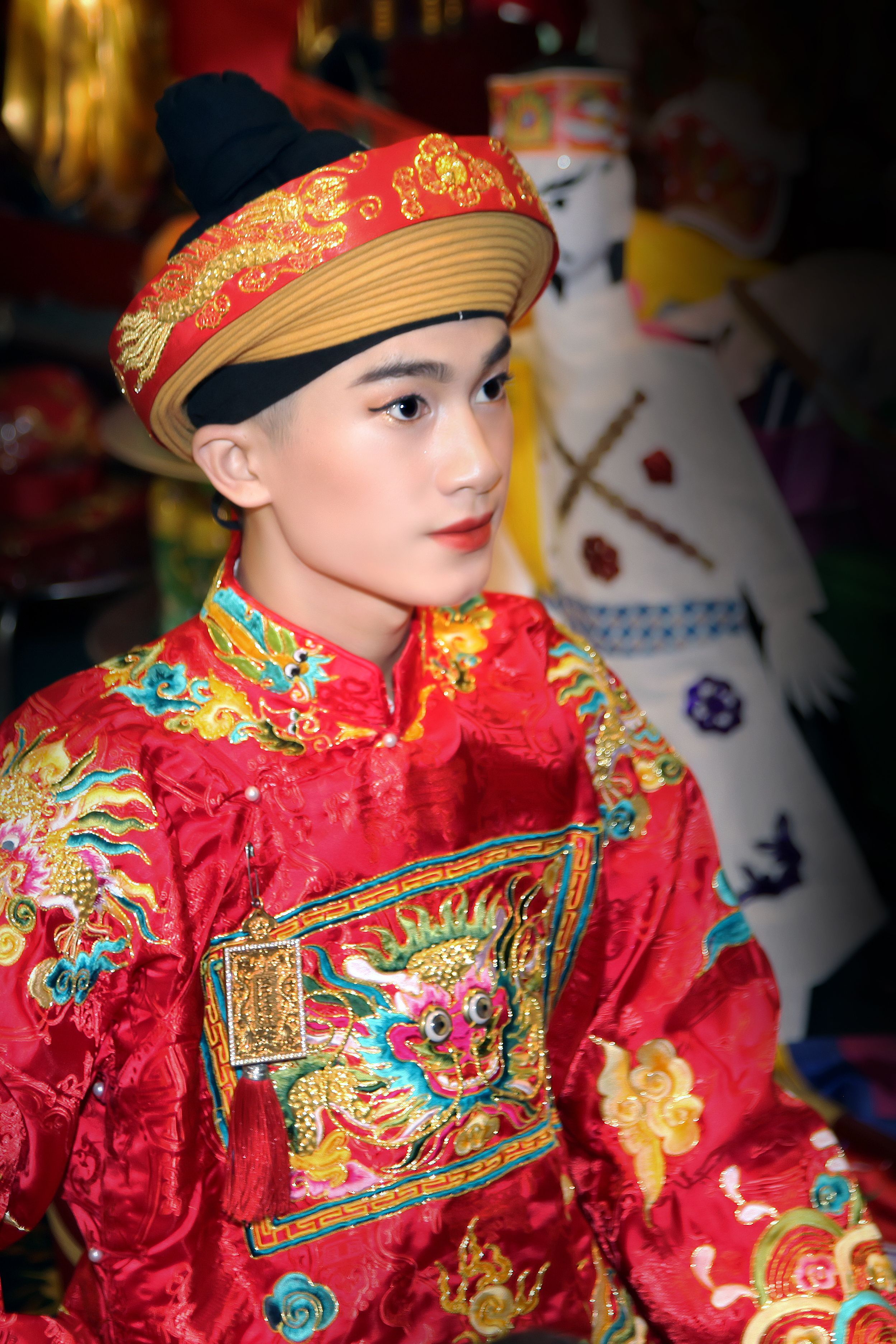 A young adult wearing traditional Chinese red embroidered wedding attire.