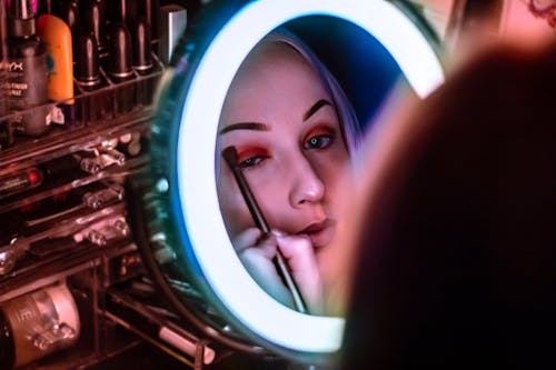 Free Woman Facing Mirror Applying Eyeshadow Stock Photo