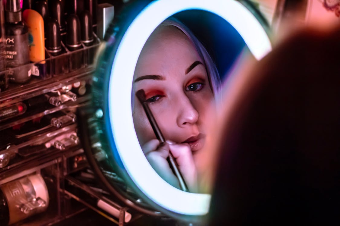 Woman Facing Mirror Menerapkan Eyeshadow