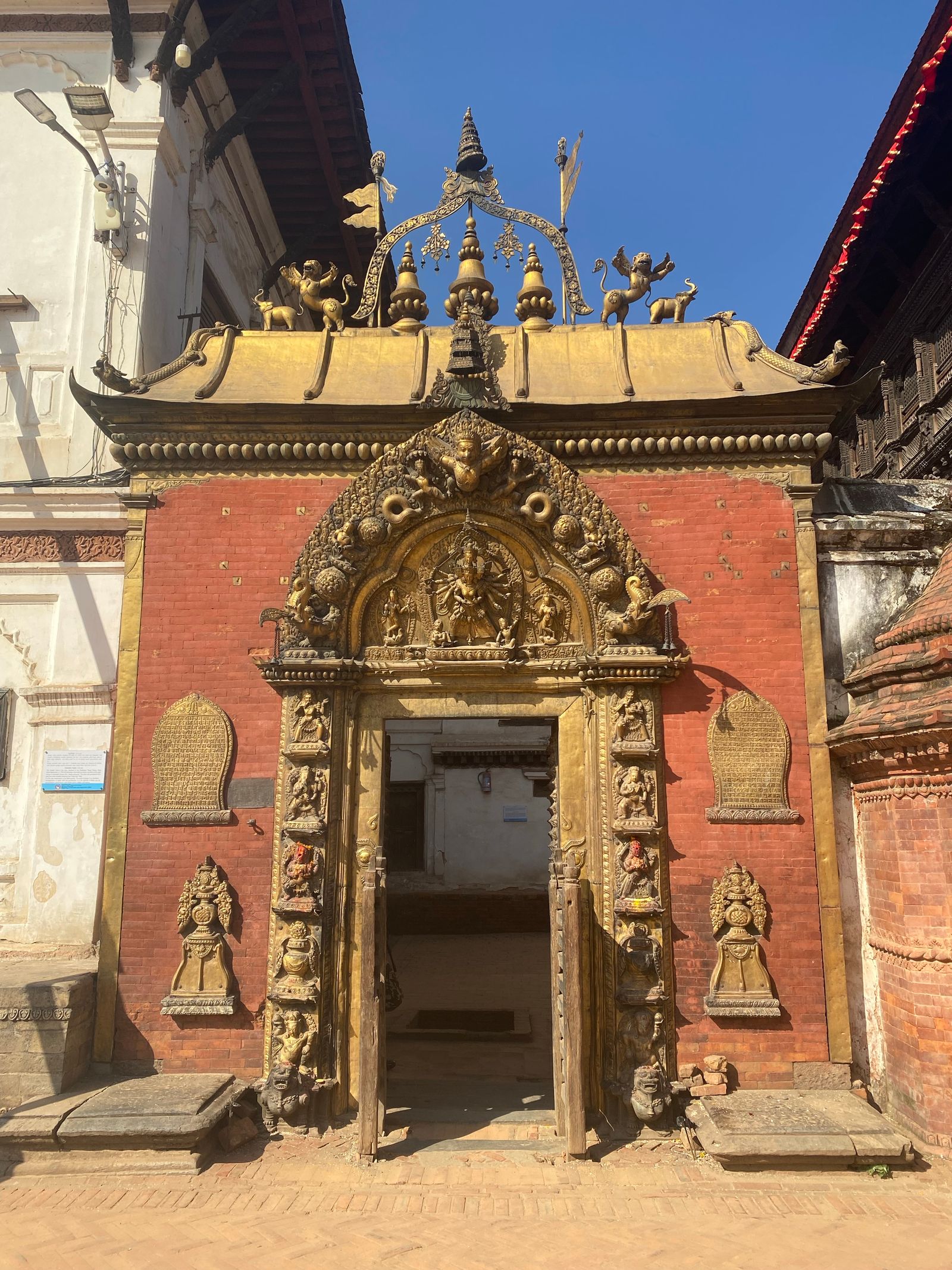 The gilded Golden Gate of Bhaktapur's royal palace, its carved torana and guardian figures set in a red brick wall