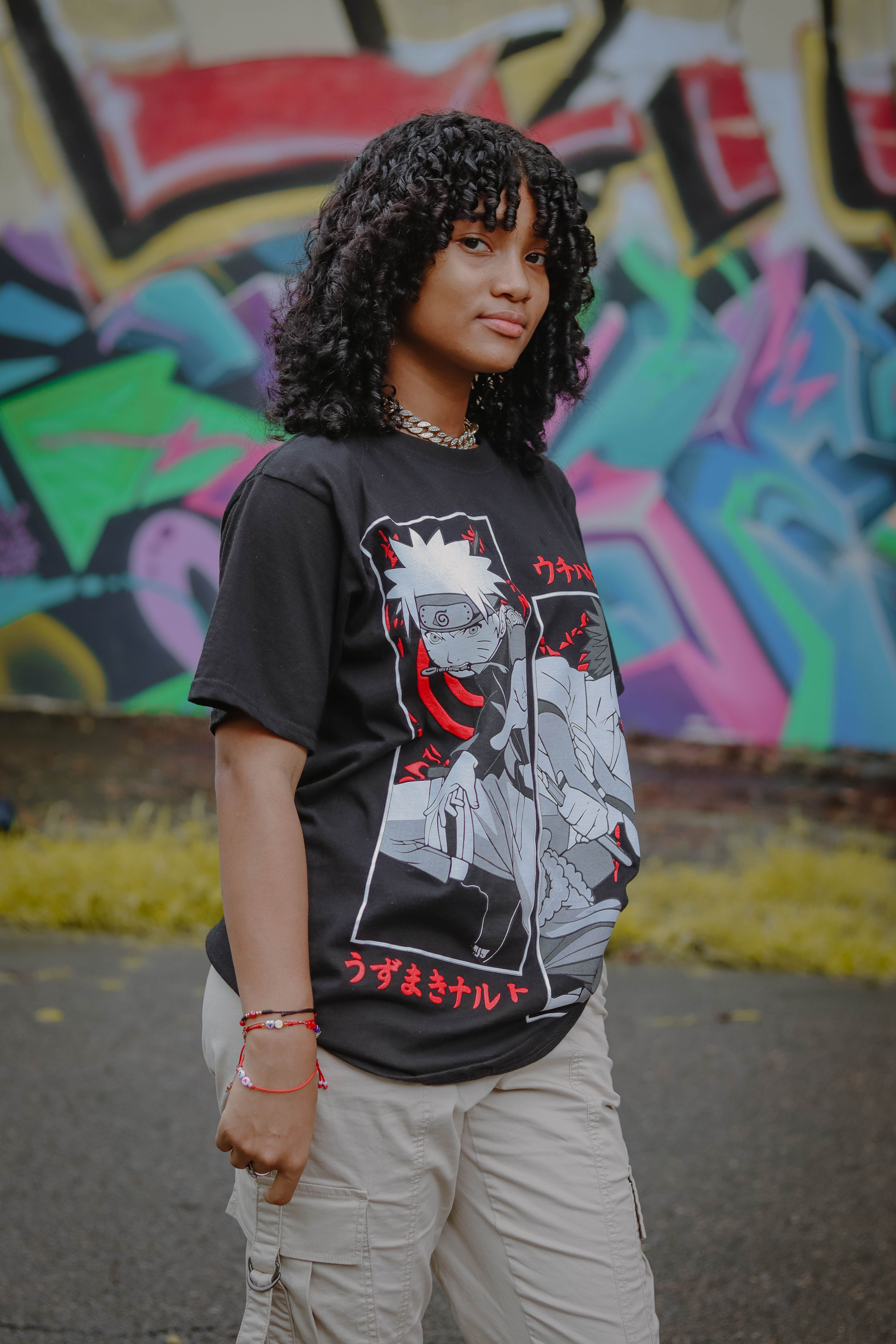 Teen girl in anime t-shirt posing in front of a colorful urban mural.