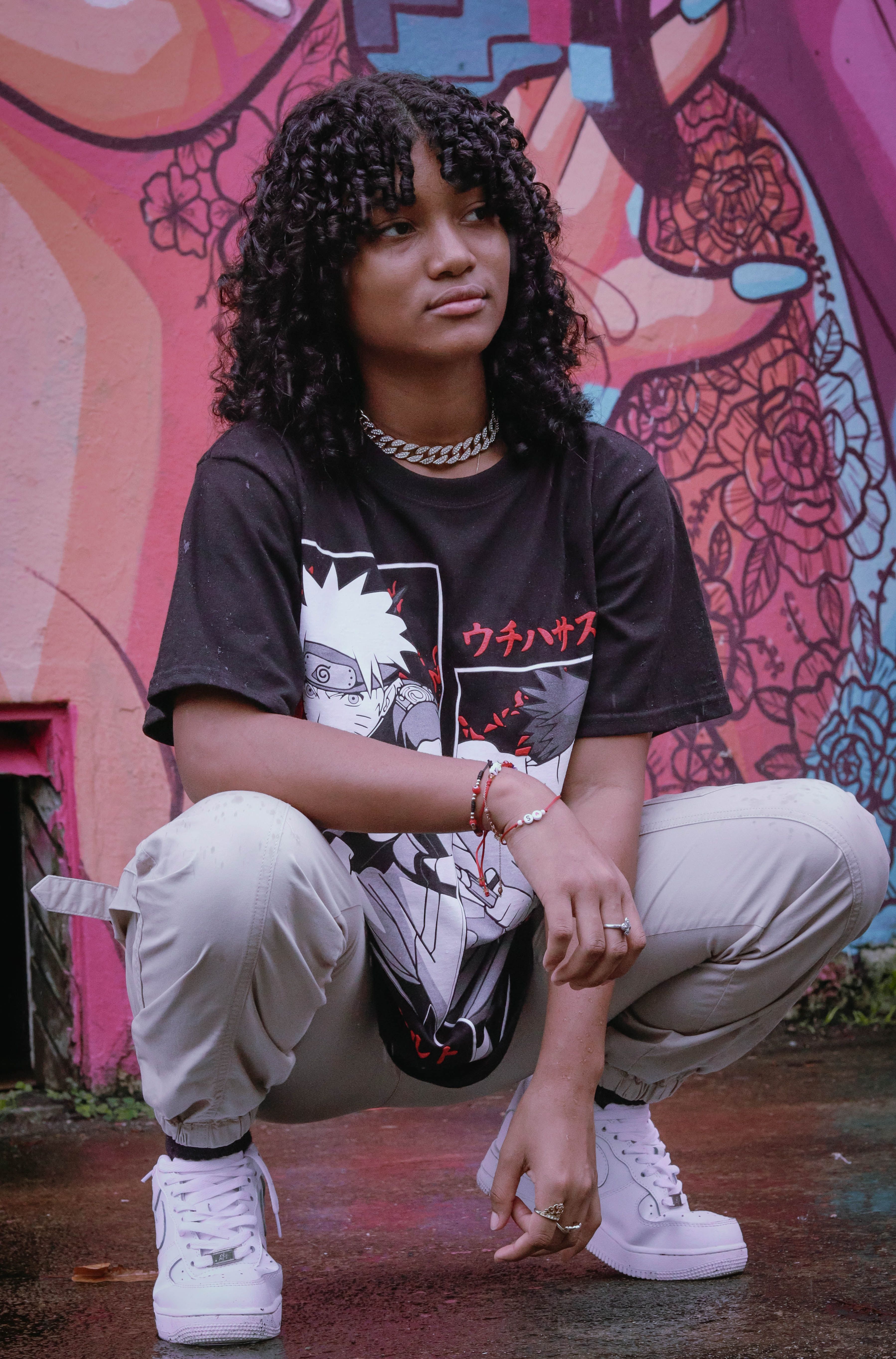 Fashion-forward teenager crouching in front of a colorful urban mural, showcasing street style.