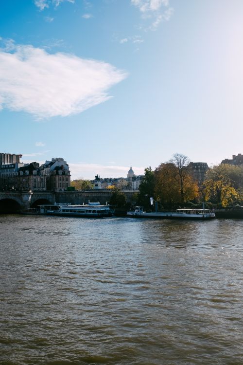 Free Panoramic view of a river with urban landscape during autumn, featuring a barge. Stock Photo