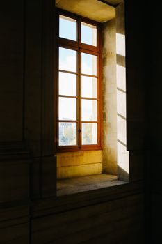 An elegant interior featuring a large sunlit window casting warm shadows inside a classic room.