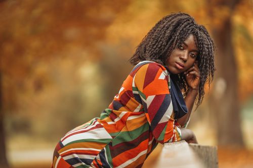 Free A woman in a colorful dress posing outdoors in an autumn park. Fashionable and vibrant. Stock Photo