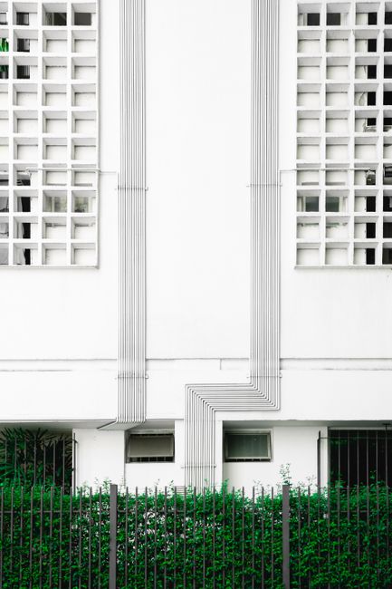 Symmetrical facade of a modern building with greenery and geometric patterns.