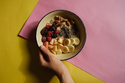 Close-up of a Person Holding a Bowl of Oats with Fruits and Nuts