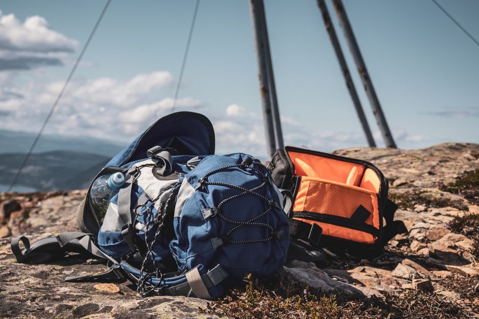 Blue and orange backpacks resting on a rocky mountain peak under a clear sky.