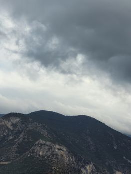 A scenic view of rugged mountains beneath a dramatic sky filled with thick, dark clouds.
