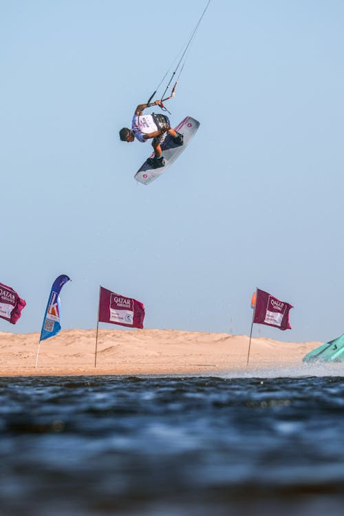 Man Jumping and Kitesurfing on Sea Shore
