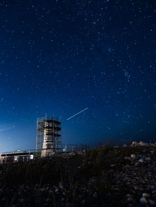 Free A mesmerizing night sky filled with stars and a prominent scaffolded tower in the foreground. Stock Photo