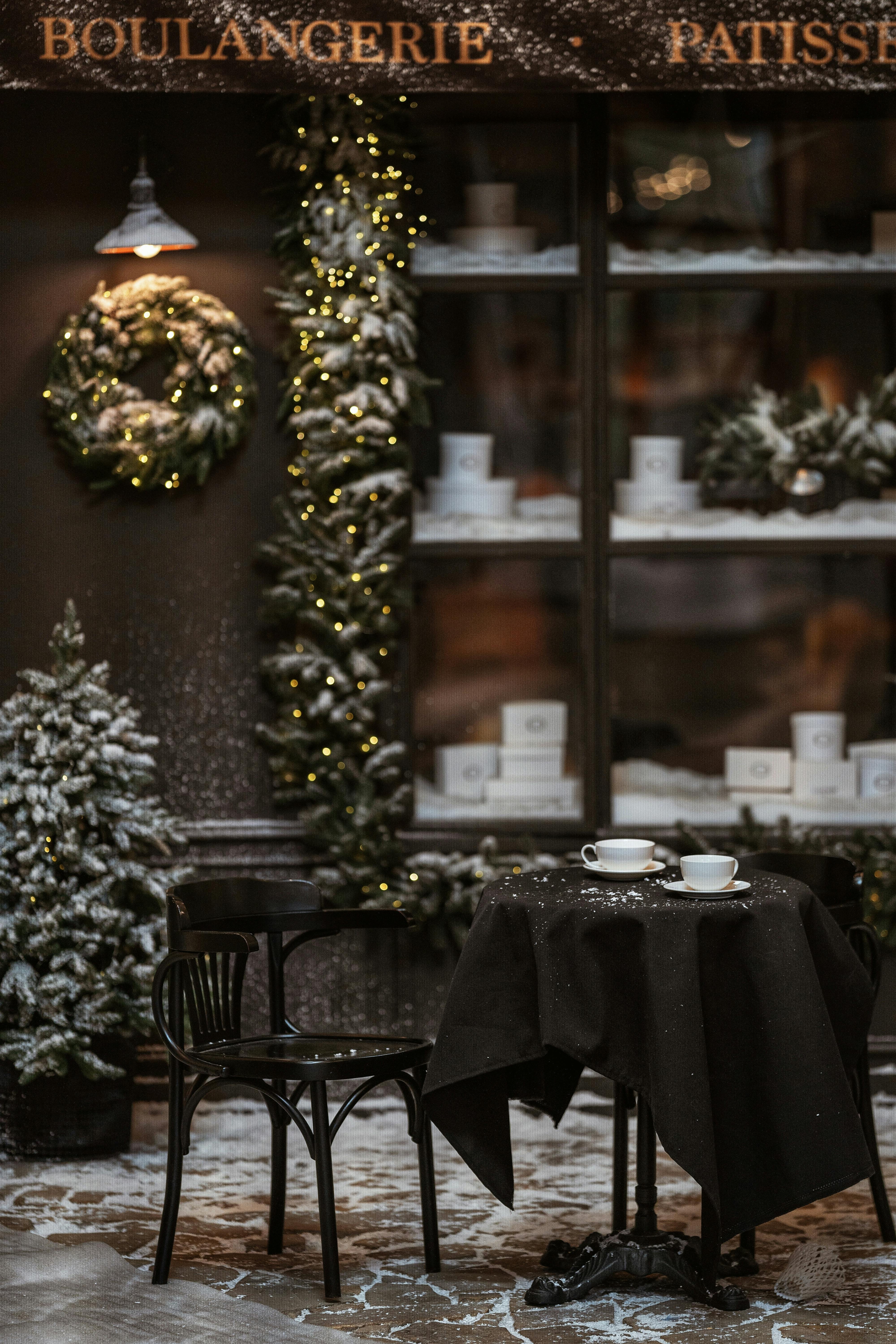 Warm inviting café setting, adorned with Christmas wreaths and snow, perfect for winter season.