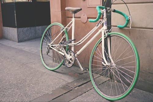 White and Green Bike Leaning on Wall