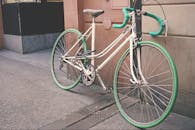 一辆绿白相间的老式自行车停在城市街道的外墙边