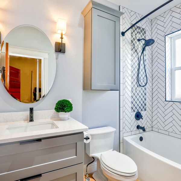Freshly cleaned bathroom with bright white tile, a round mirror, and spotless glass