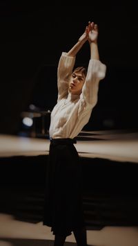 Bailarín improvisando con los brazos en alto en una sala en penumbra