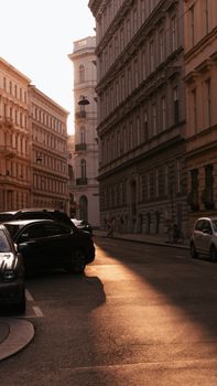 A picturesque city street scene during sunset with elegant buildings and parked cars.