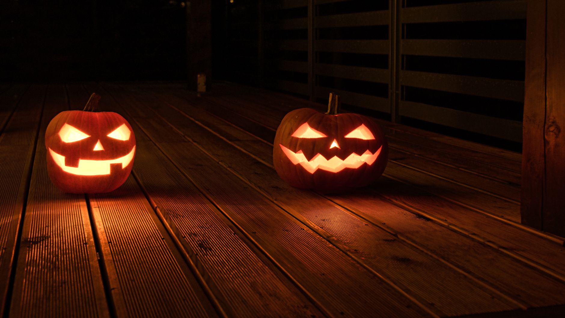 Illuminated jack-o-lanterns with carved faces create a spooky Halloween ambiance on a wooden deck at night. — free online jigsaw puzzle on JigsawPuzzlesFreeOnline.org