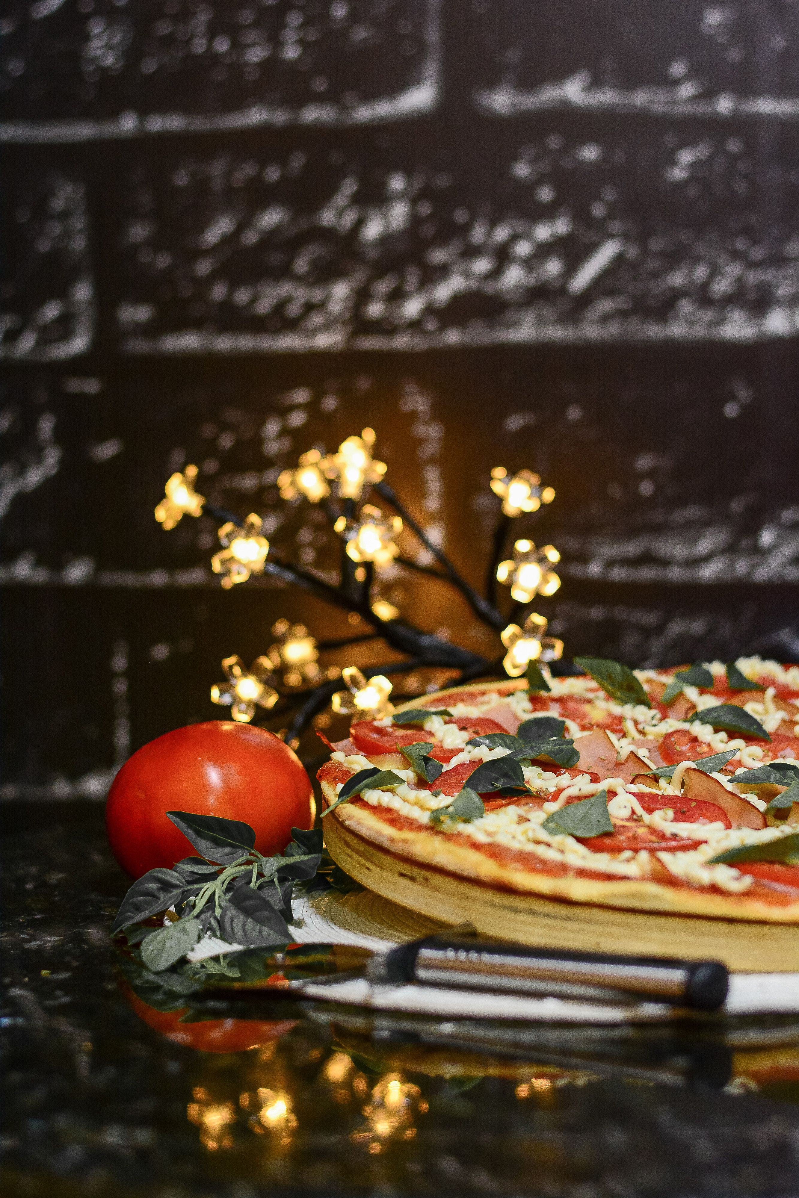 Close-up of a fresh pizza with tomatoes and basil on a plate with a cozy lighting backdrop.