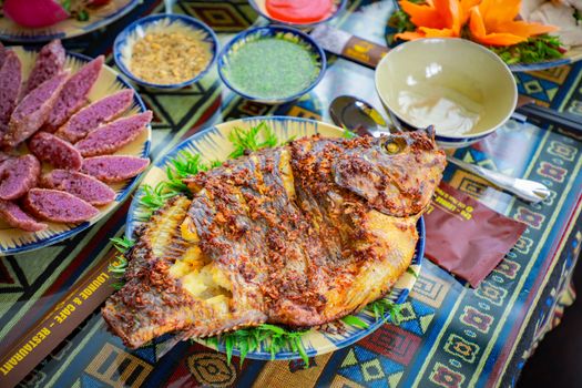 A vibrant spread featuring grilled fish and colorful sides on a patterned tablecloth.