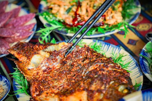 Close-up of spicy grilled fish served with vibrant herbs and vegetables, a culinary delight.