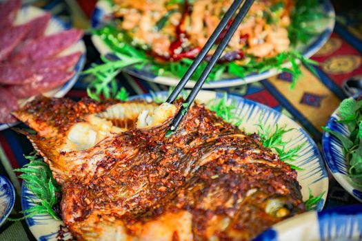 A delicious spicy grilled fish dish served on a colorful table setting with vegetables.
