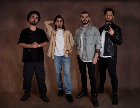 Four men in casual and fashion-forward attire posing confidently in a studio.