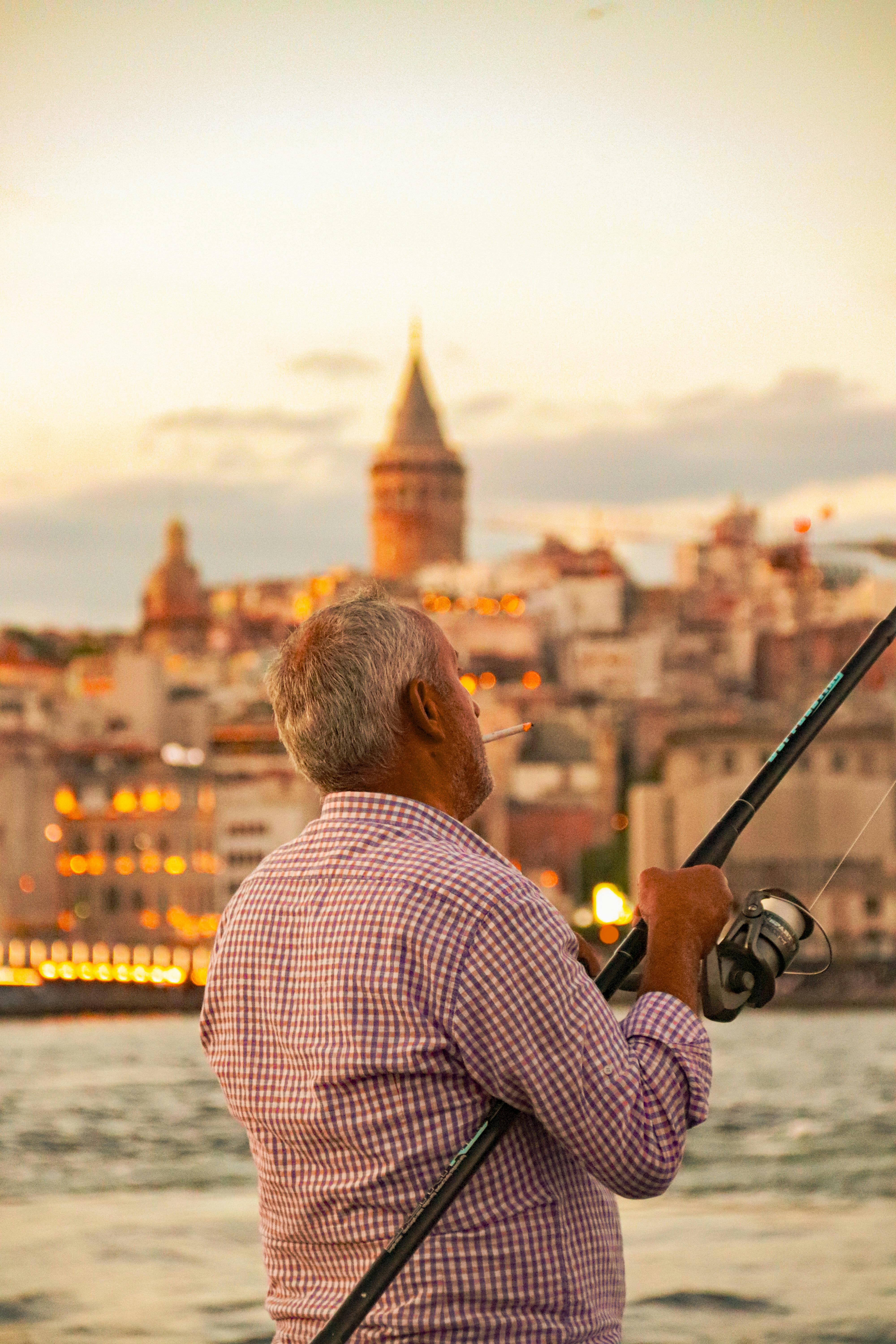 fisherman smoking on sea shore in istanbul at sunset