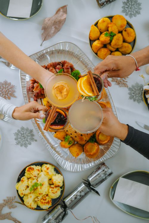 Free A festive dinner table with various dishes and people clinking glasses for a celebration. Stock Photo