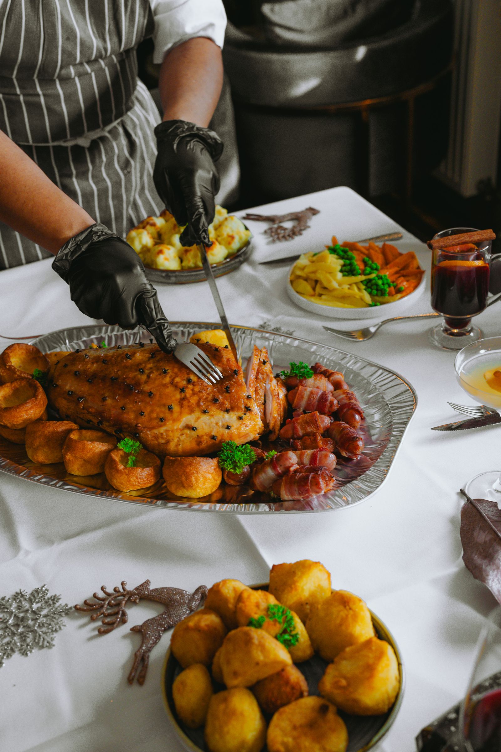A chef carving roasted meat beside golden Yorkshire puddings