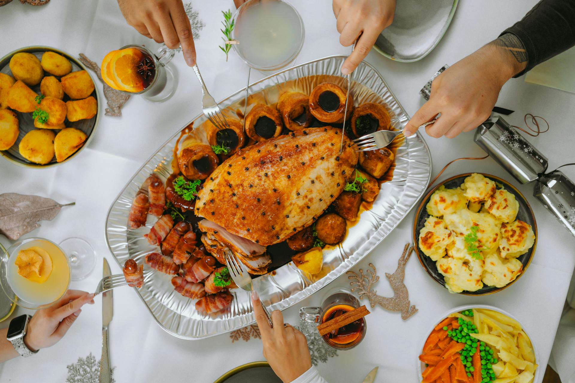 People Cutting Roasted Meat during a Meal Together