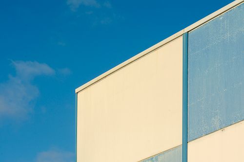Free A minimalist urban building facade contrasted against a bright blue clear sky. Stock Photo
