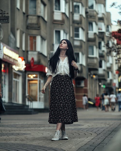 Young Woman in a Skirt Standing on the Sidewalk 
