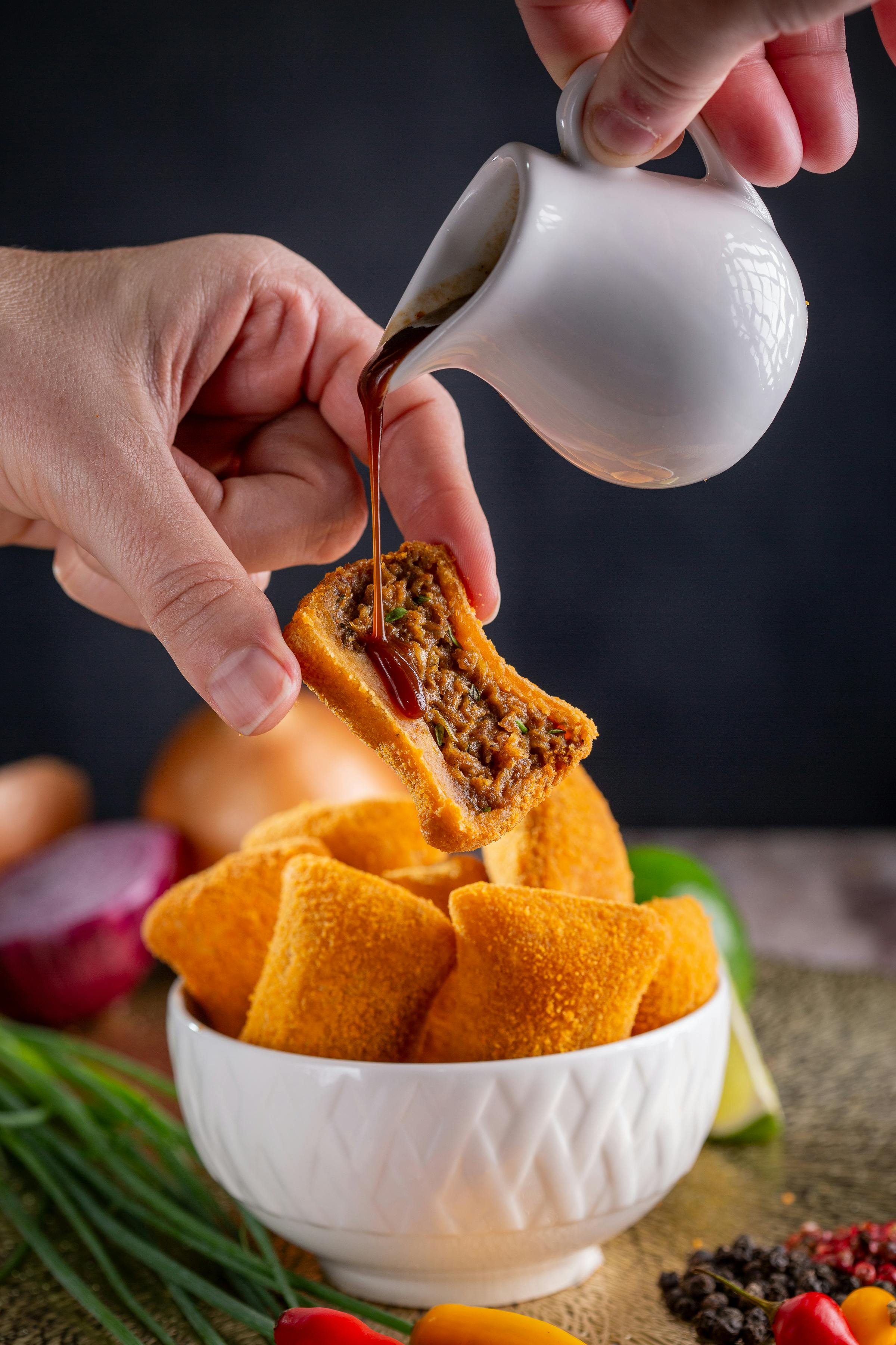 person pouring sauce on food