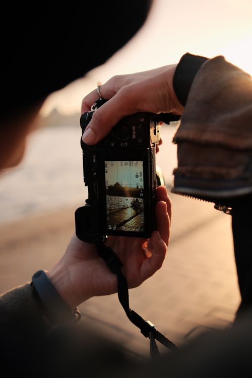 Free Close-up shot of a person photographing a sunset with a digital camera on a beach. Stock Photo