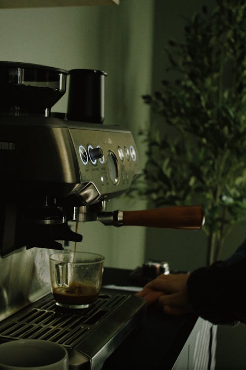 Person Making Coffee in a Coffee Machine 