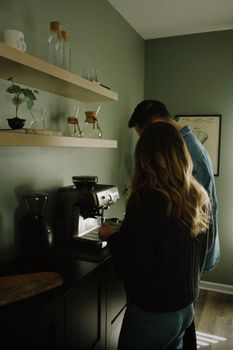 A couple making coffee together using a coffee machine in a stylish kitchen