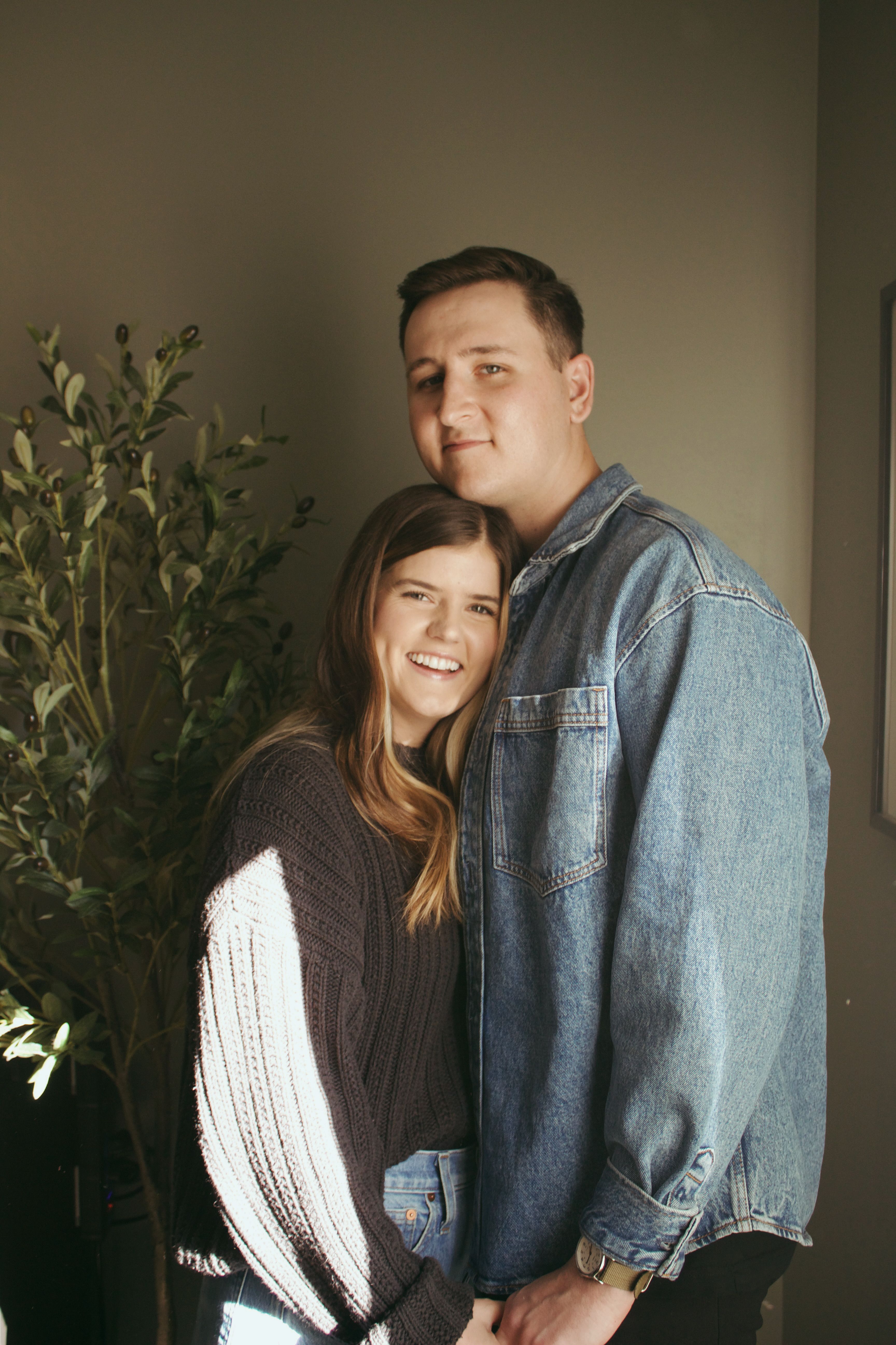 Happy couple embracing indoors, showcasing casual fashion and togetherness.