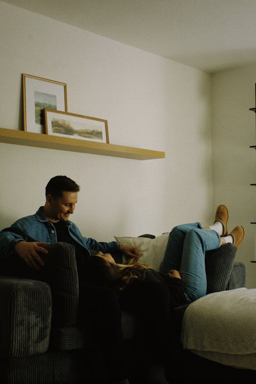 Free Man Sitting and Woman Lying Down on Couch Stock Photo