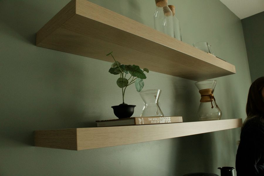 Floating shelves holding books and plants against a painted wall