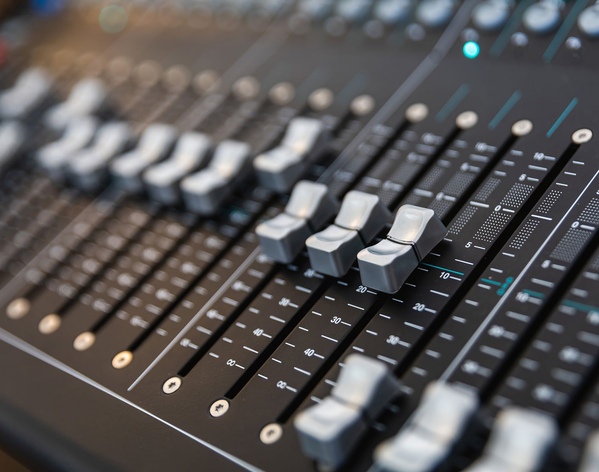 High-quality close-up of a sound mixing console with sliders and buttons for audio control.