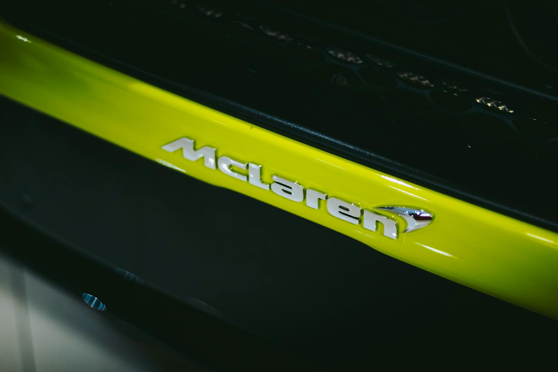 A striking close-up view of a McLaren car logo on a lime green hood, emphasizing design and luxury.