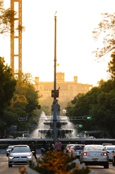 Scenic view of Chapultepec Castle from a bustling street in Mexico City during sunset.