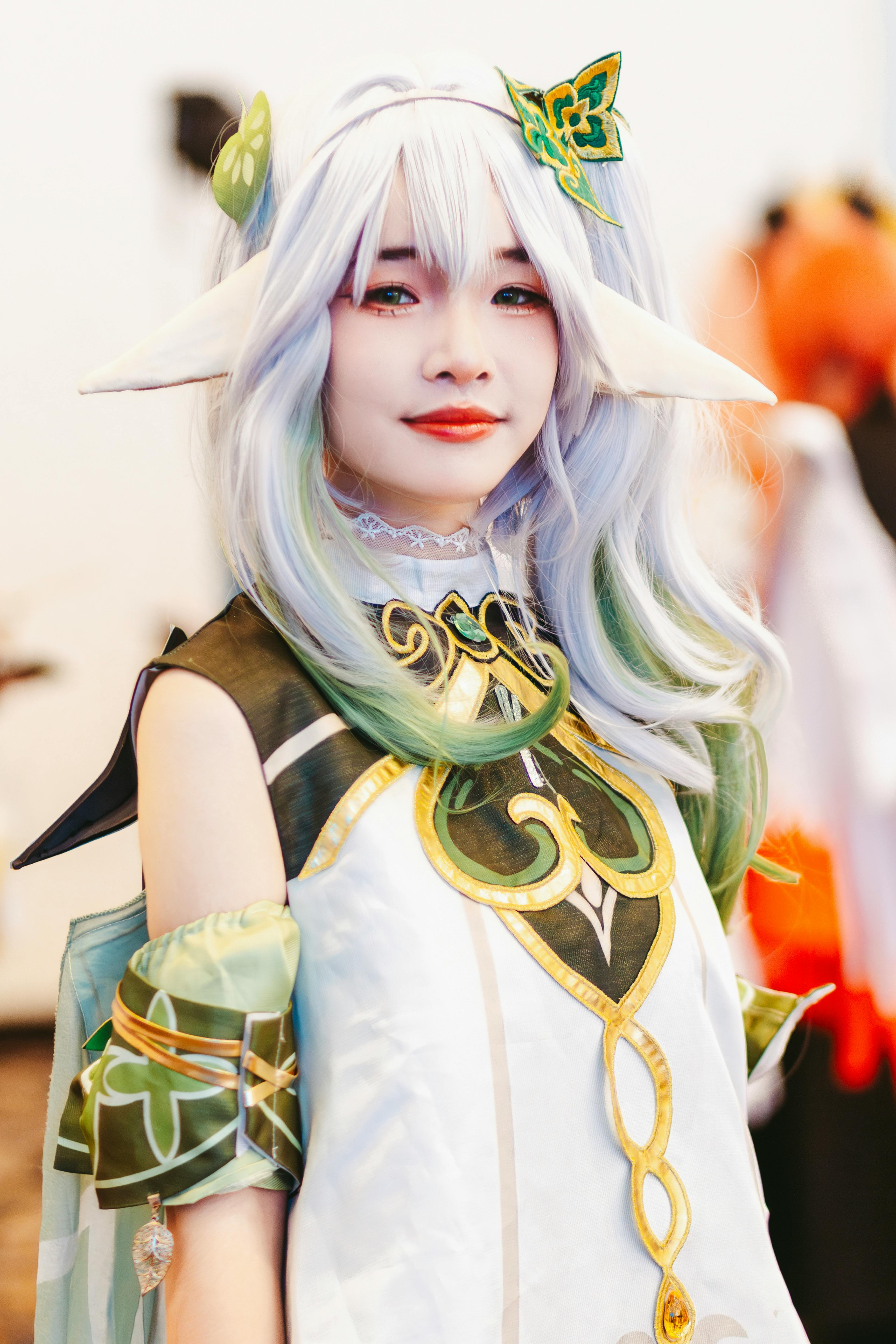Vibrant portrait of a woman in elaborate cosplay costume with green and white details.